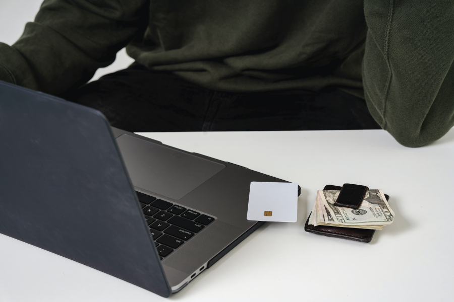 Photo of a desk with a laptop, credit card, wallet and cash