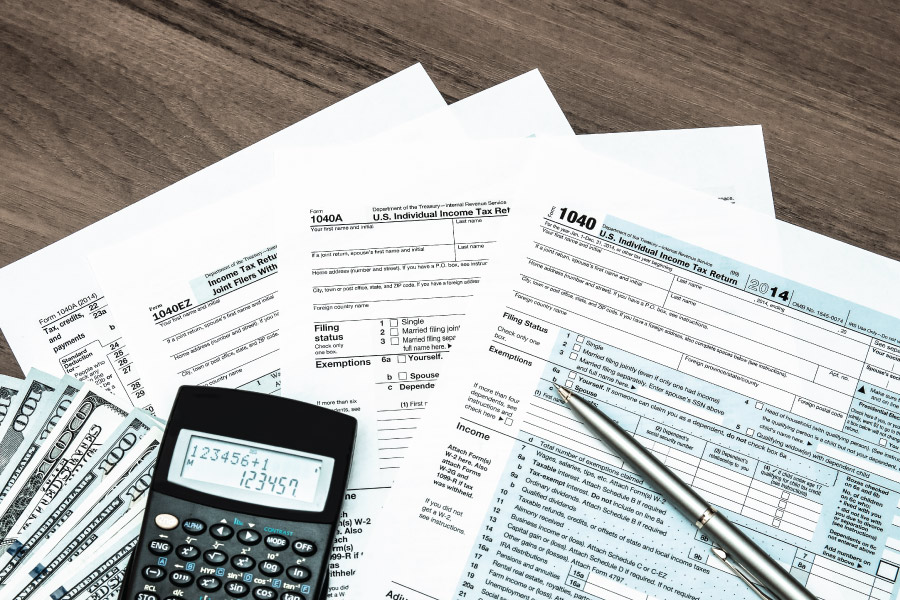A variety of tax documents, a calculator and a pen sitting on a table