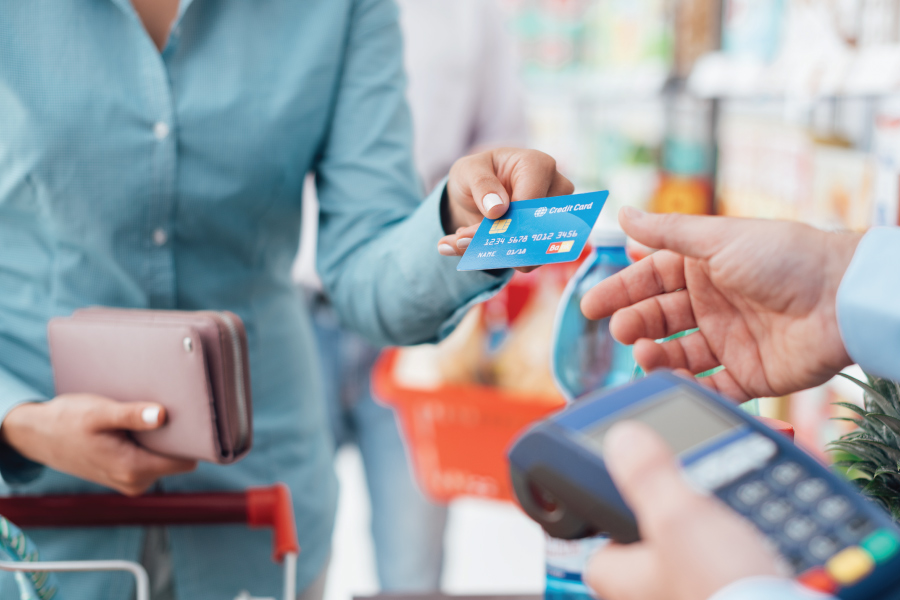 A person handing a credit card to a salesperson with a credit card machine