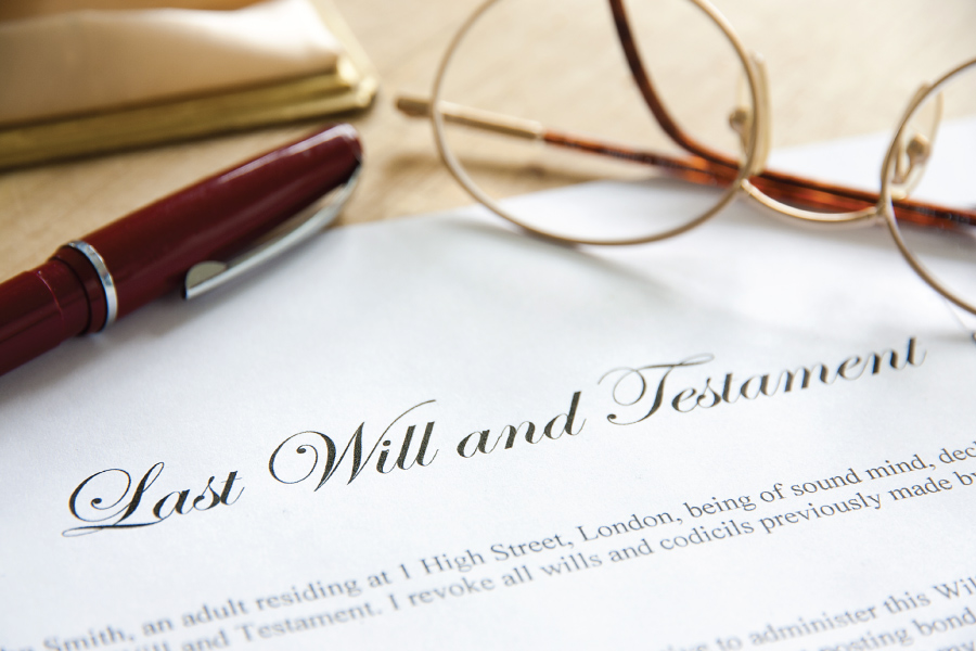 Close up of a will document with glasses and a pen on top of the paper