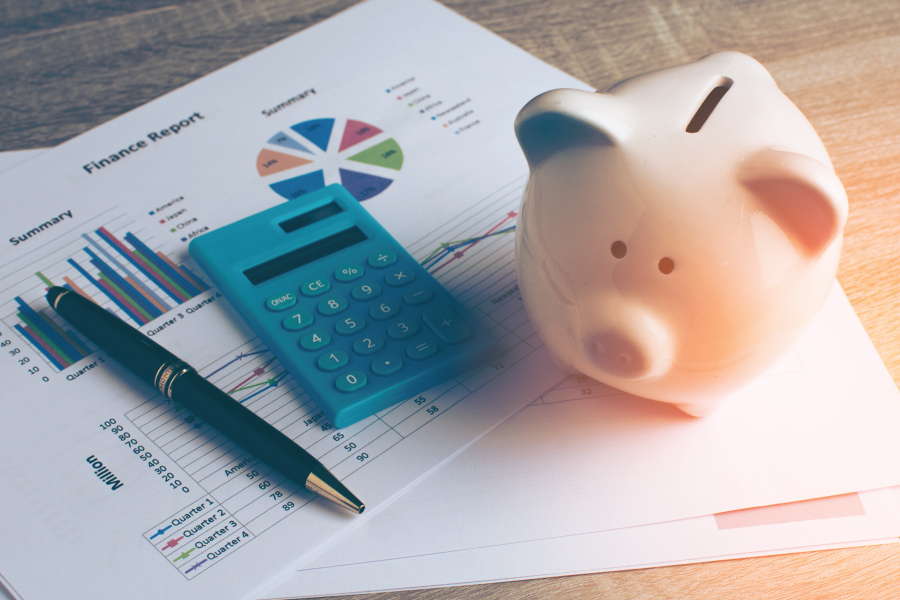 Papers, a calculation, a pen and a piggy bank on a desk