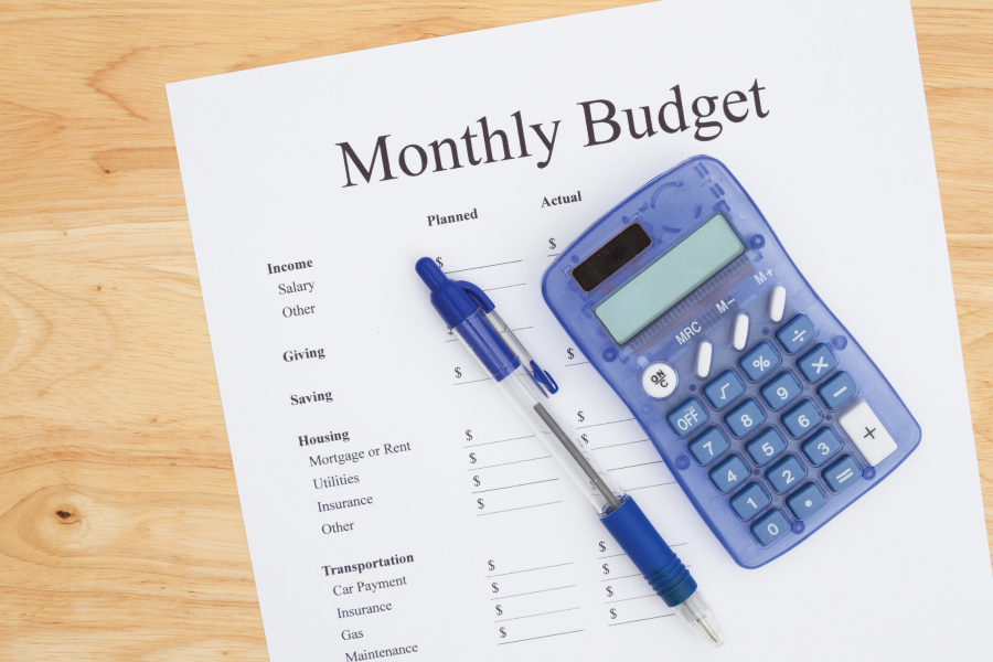 A monthly budget worksheet with a calculator and pen on top of it