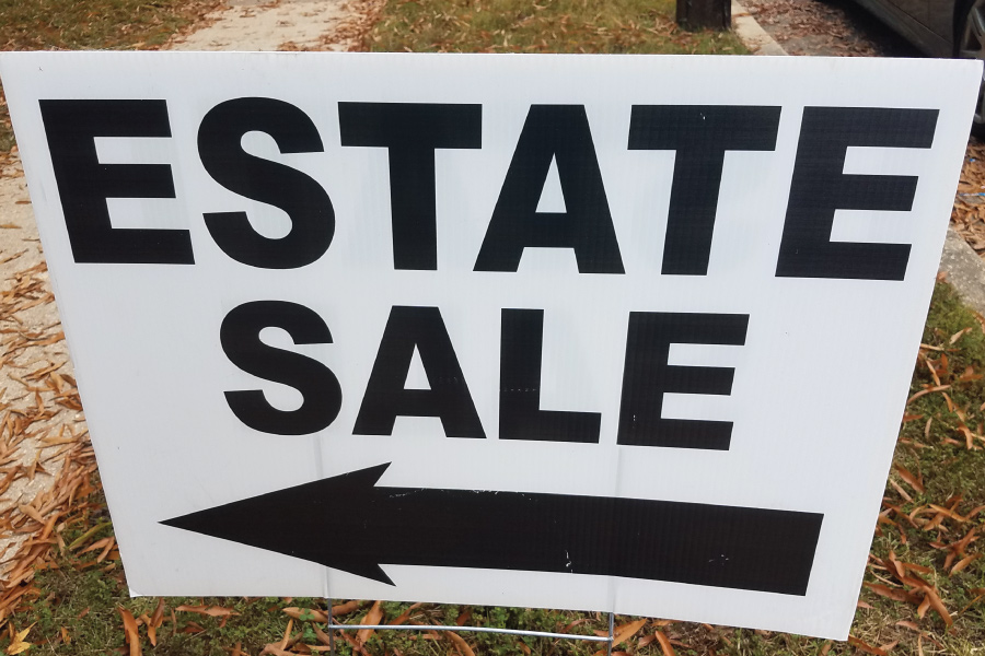 A yard sign with an arrow and text that reads, "estate sale"