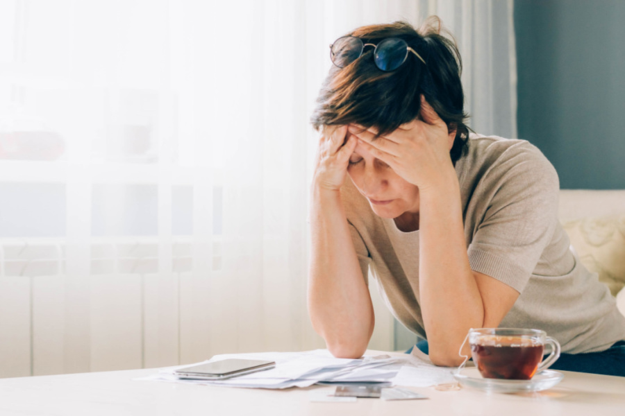 stressed woman at a desk with tea and paperwork