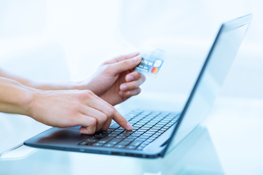 hands on a laptop keyboard holding a credit card