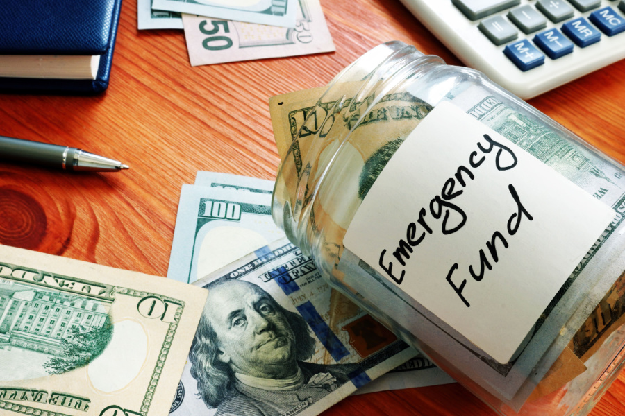 emergency fund jar on a desk with cash in and around it