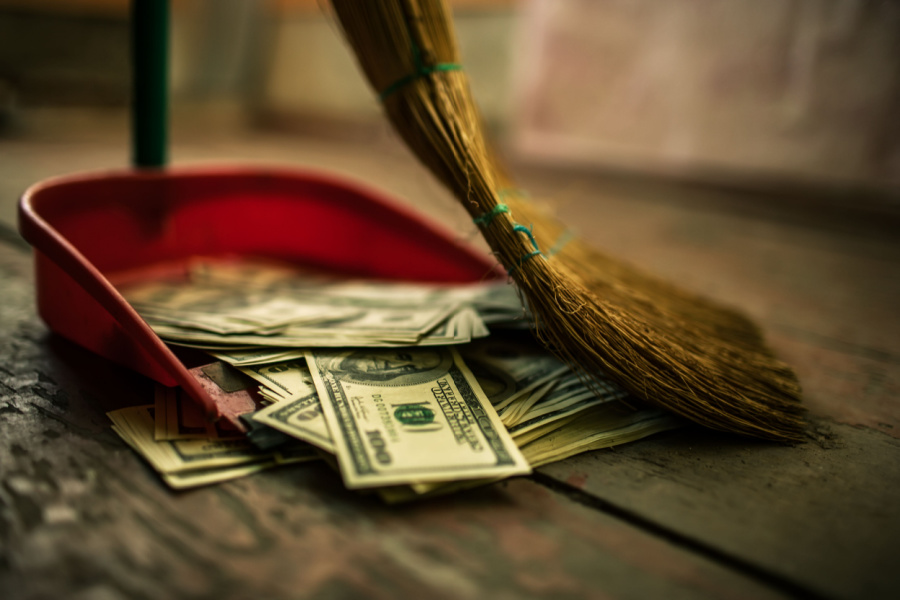 broom sweeping one hundred dollar bills into a dust pan
