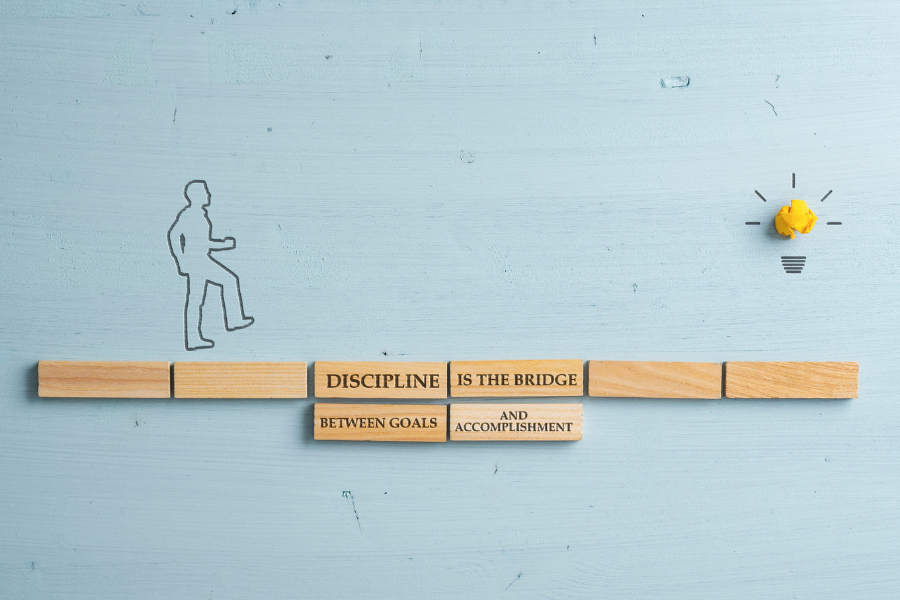 illustration of a main crossing a bridge made of blocks that read "discipline is the bridge between goals and accommplishment"