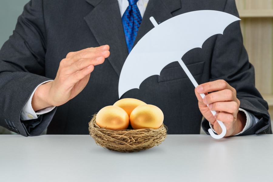 man in a suit holding an umbrella over his nest of golden eggs