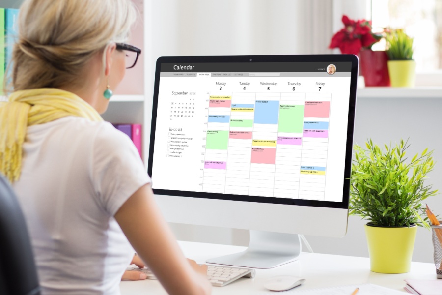 woman at her computer managing a color-coded calendar