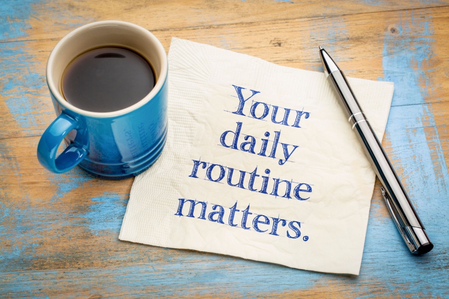 cup of coffee on a table with a napkin that reads "your daily routine matters".